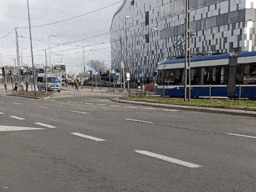 a blue and white trolley is going down a street with a building in the background