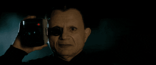 a man is holding a camera in front of his eye