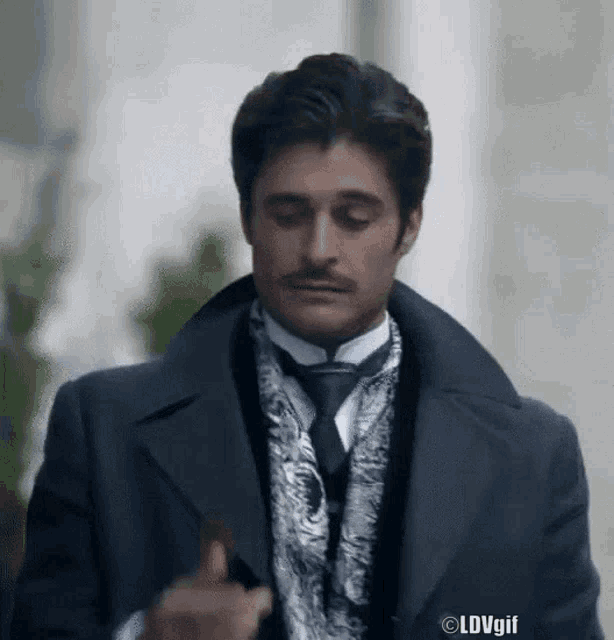a man in a suit and tie with a mustache is walking down a street .