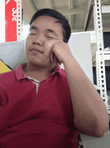 a man in a red shirt rests his hand on his face