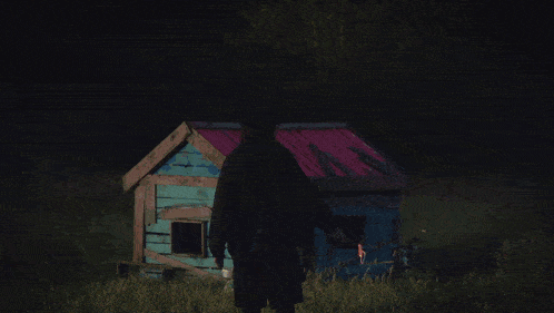 a man stands in front of a burning cabin at night