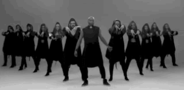 a black and white photo of a group of people dancing in a row .