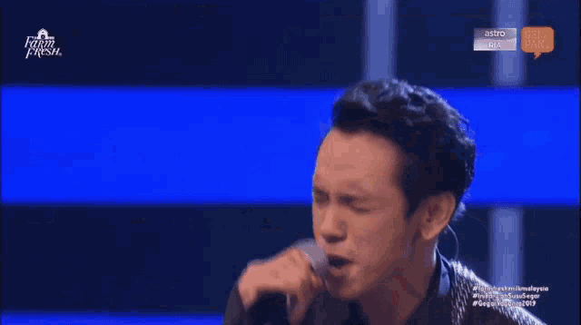 a man is singing into a microphone on a television show called farm fresh