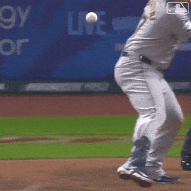 a baseball player is swinging at a ball on a field with a sign that says live in the background