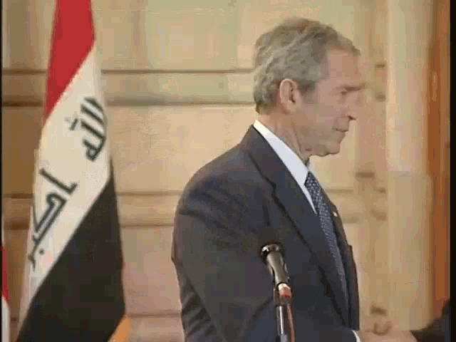 a man in a suit stands in front of a microphone in front of a flag that says ' islamic republic ' on it