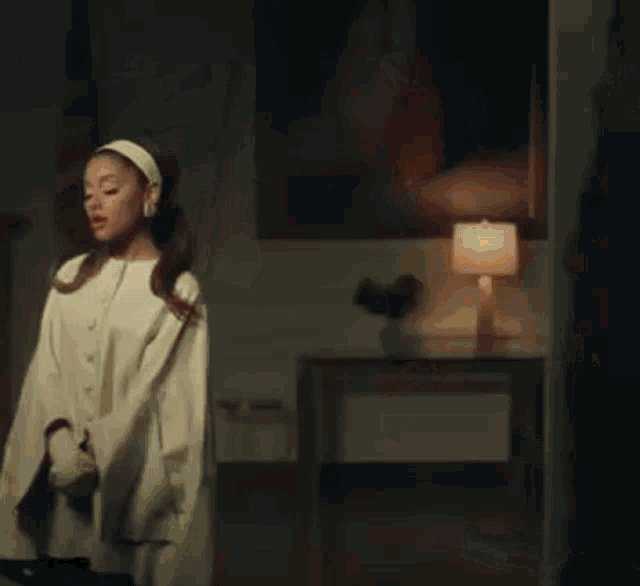 ariana grande is wearing a white headband and a white coat in a room .