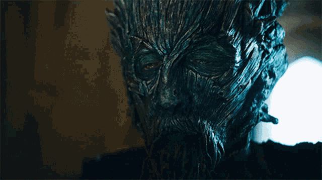 a close up of a tree face with a beard and green eyes