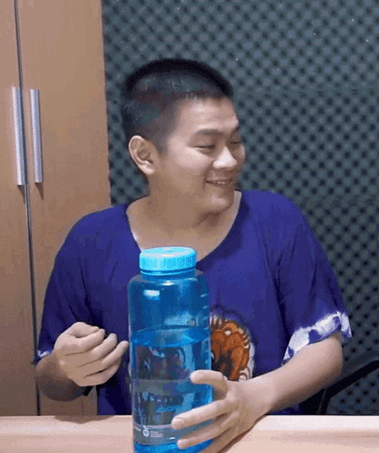 a man in a blue shirt holds a blue water bottle