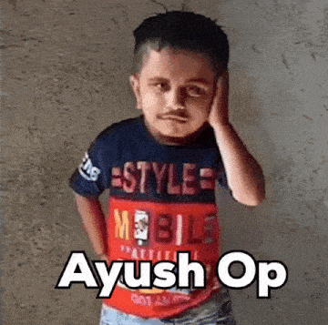 a young boy wearing a mobile t-shirt is standing in front of a wall with his hand on his ear .