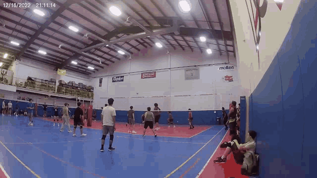 a group of people are playing basketball in a gym with a sign that says molten