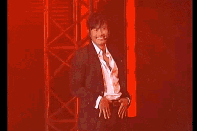 a man wearing a suit and tie is smiling with a microphone around his neck .