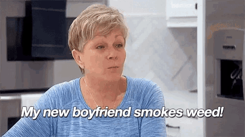 a woman in a blue shirt is sitting in a kitchen and talking about her new boyfriend smoking weed .