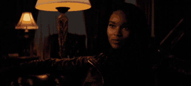 a woman in a pink dress stands in the dark