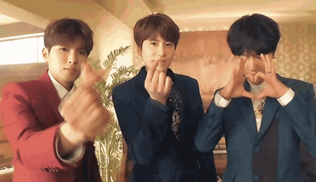 three men in suits make a heart with their hands