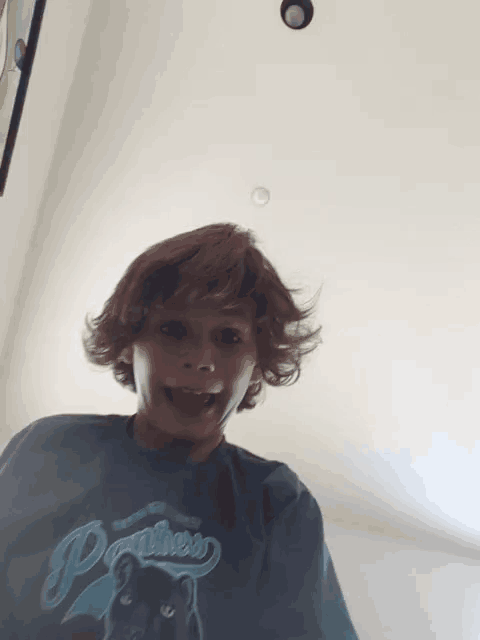 a young boy wearing a panthers t-shirt makes a funny face