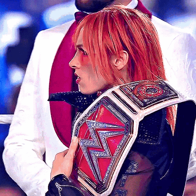 a woman with red hair is wearing a wrestling belt