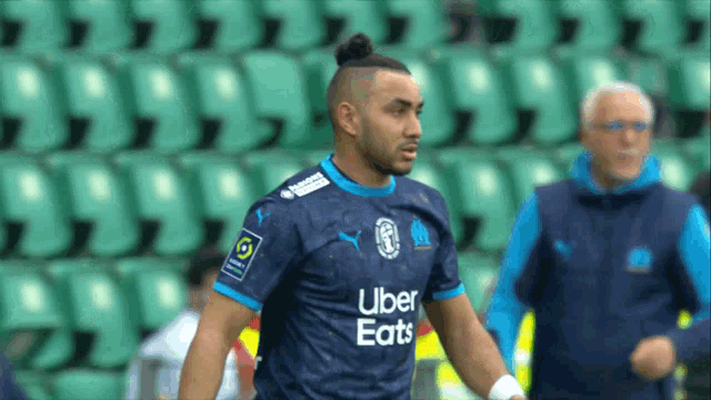 a soccer player wearing an uber eats jersey stands in front of empty seats