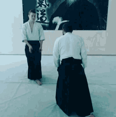 a man in a white shirt and black pants stands next to another man