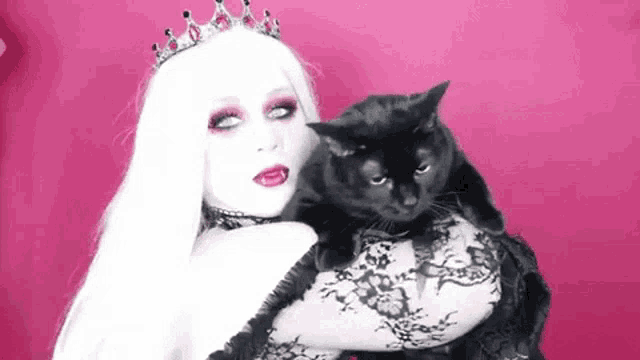 a woman with white hair is holding a black cat .
