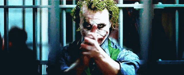the joker is holding a knife and pointing it at the camera .