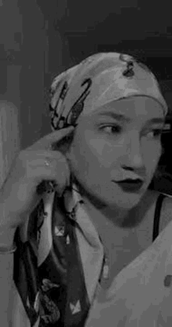 a black and white photo of a woman wearing a scarf and a head scarf .