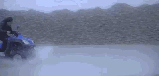 a woman in a blue jacket is running on a dirt road in the fog .