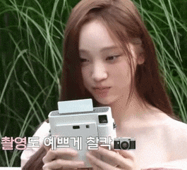 a woman is holding a polaroid camera in her hands with korean writing on the bottom