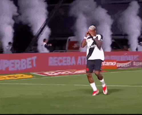 a soccer player stands on a field with smoke coming out of the stands