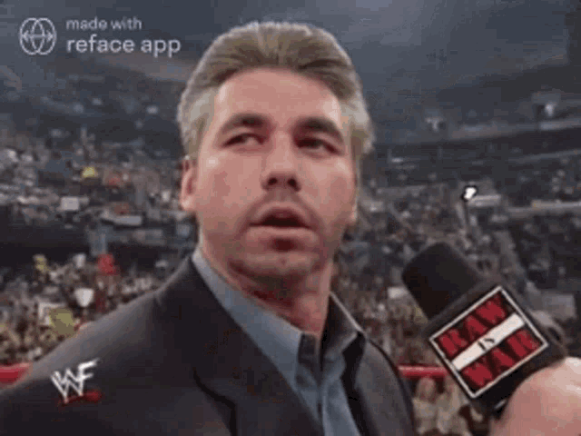 a man in a suit is holding a microphone in his hand and talking into it .
