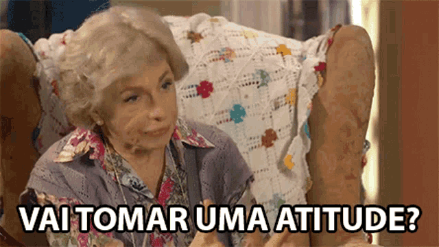 an elderly woman is sitting in a chair with the words vai tomar uma atitude written below her