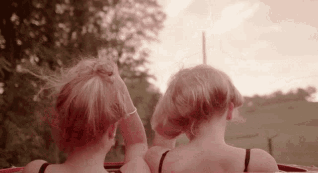 two girls are sitting in the back of a car looking at the sunset