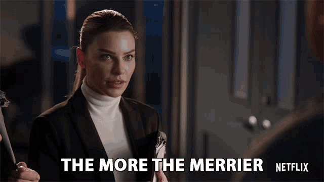 a woman in a suit and white turtleneck says the more the merrier