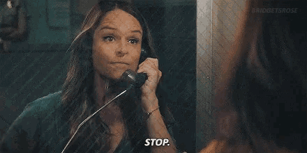 a woman is talking on a telephone in a jail cell and making a funny face .