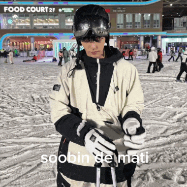 a man wearing a helmet and goggles stands in the snow in front of a food court