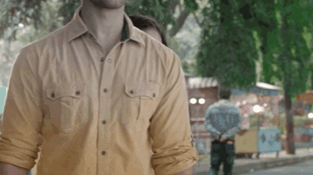a man in a yellow shirt is standing on a sidewalk