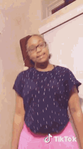 a girl wearing a blue shirt and pink shorts has a tiktok logo on the bottom right