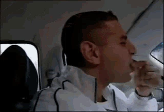 a man drinking water from a bottle while sitting in a car