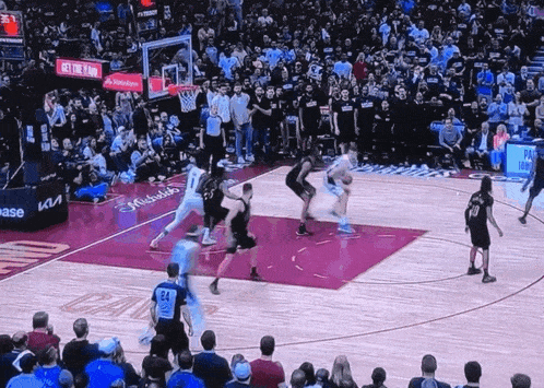 a basketball game is being played in front of a crowd with a michelle obama ad on the wall