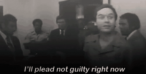 a man in a suit and tie is standing in front of a group of men and says i 'll plead not guilty now