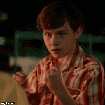 a young boy in a plaid shirt is holding his fist up with the words `` fight me '' written on it .