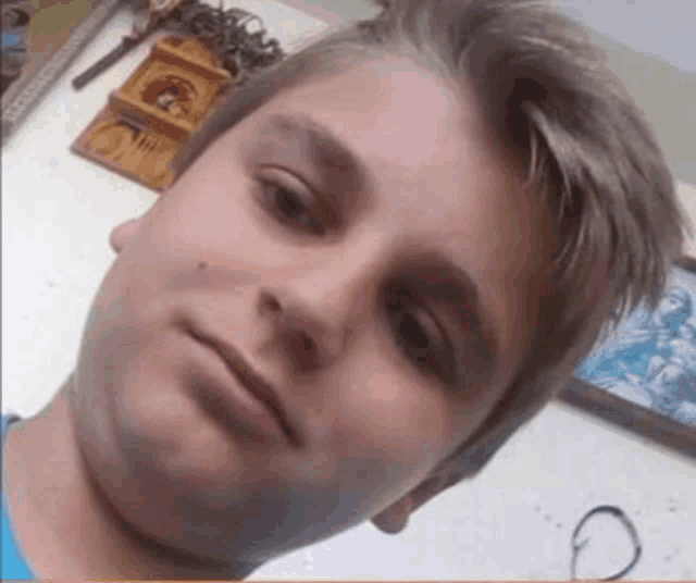 a young boy taking a selfie in front of a wall with a clock on it
