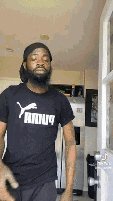 a man wearing a yamuq t-shirt is standing in front of a door