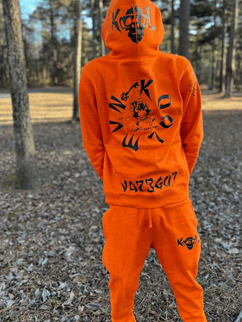 a person wearing an orange hoodie and sweatpants with the word king on the back
