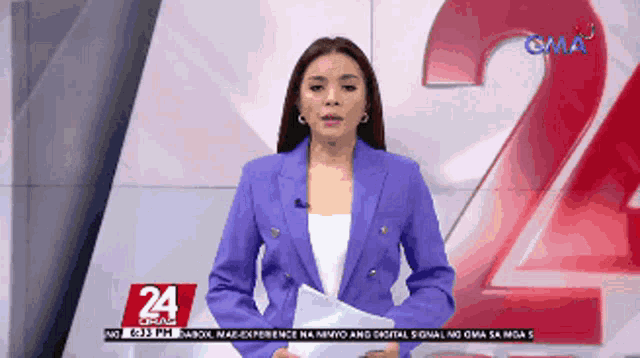 a woman in a purple jacket stands in front of a sign that says gma 24