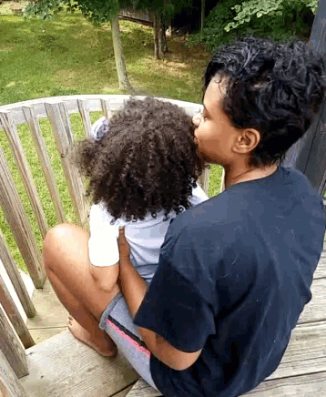 a woman in a black shirt is holding a little girl