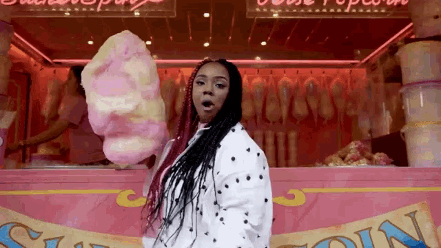 a woman stands in front of a cotton candy stand