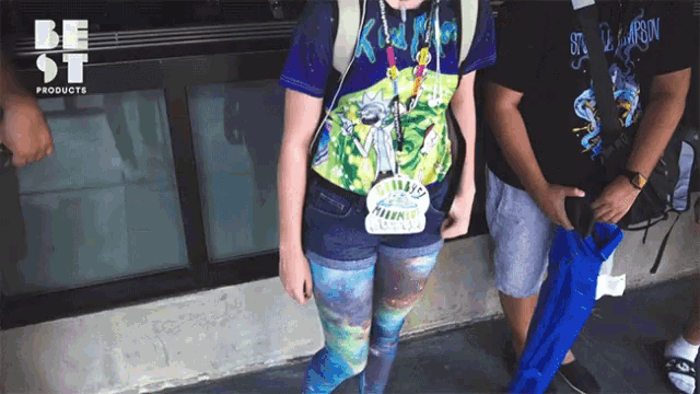 a girl wearing a rick and morty shirt stands next to a man