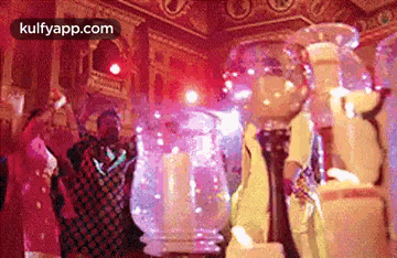 a group of people are dancing in a room in front of a large glass bowl .
