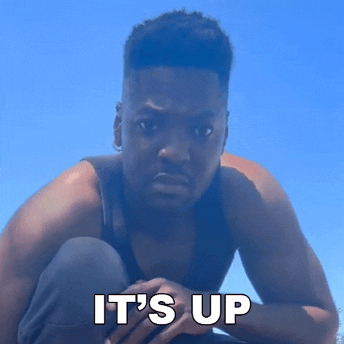 a man is squatting down with the words `` it 's up '' written on his face .