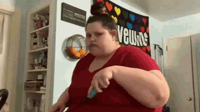 a woman in a red shirt is holding a knife in front of a sign that says ' velours '